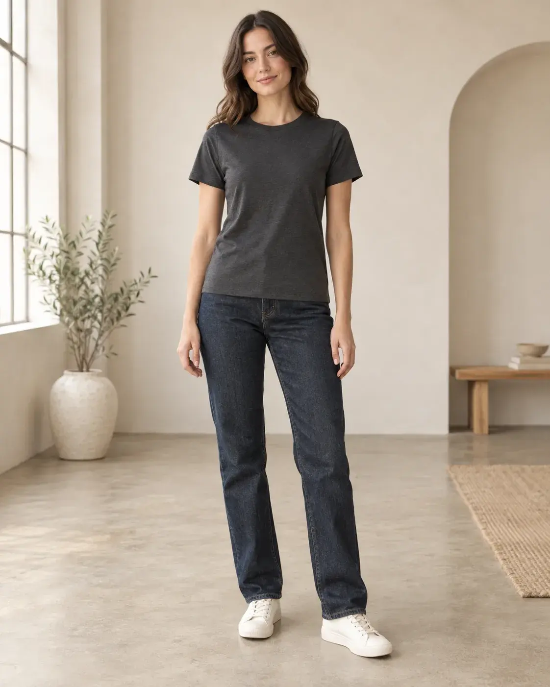 Woman wearing a charcoal T-shirt and jeans indoors before changing clothes